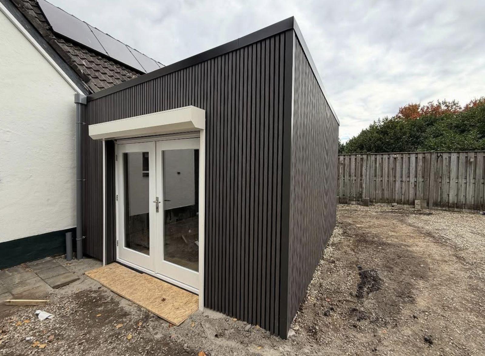 Moderne uitbouw met zwarte gevelbekleding, gerealiseerd door Projectbouw Aannemers B.V.
