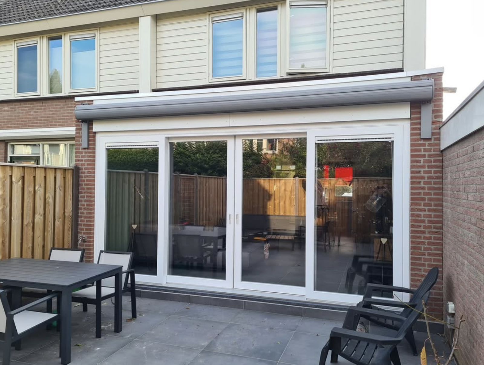 Uitbouw met brede witte schuifpui en zonwering