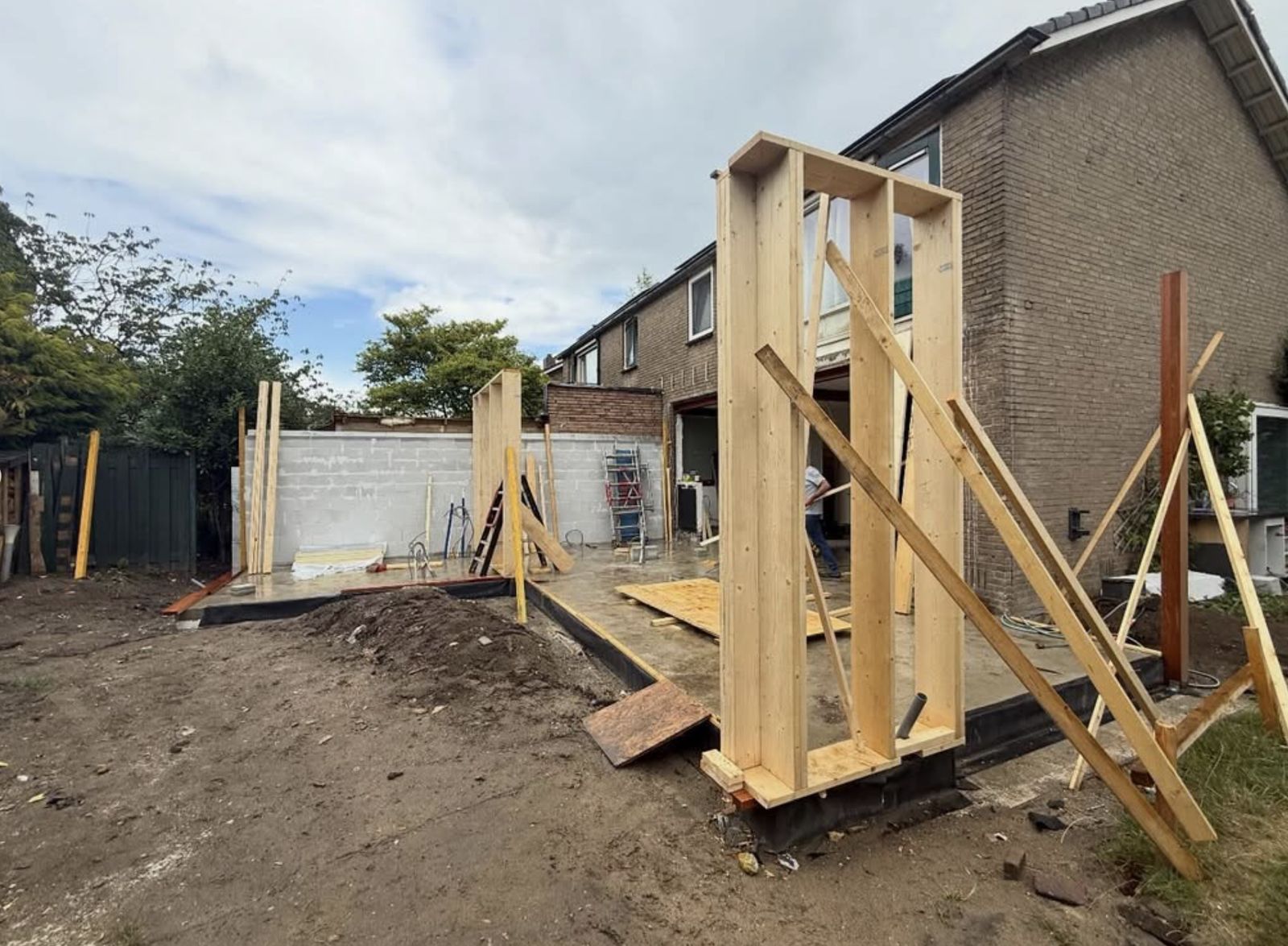 De opgeleverde aanbouw met berging en bestrating in aanleg