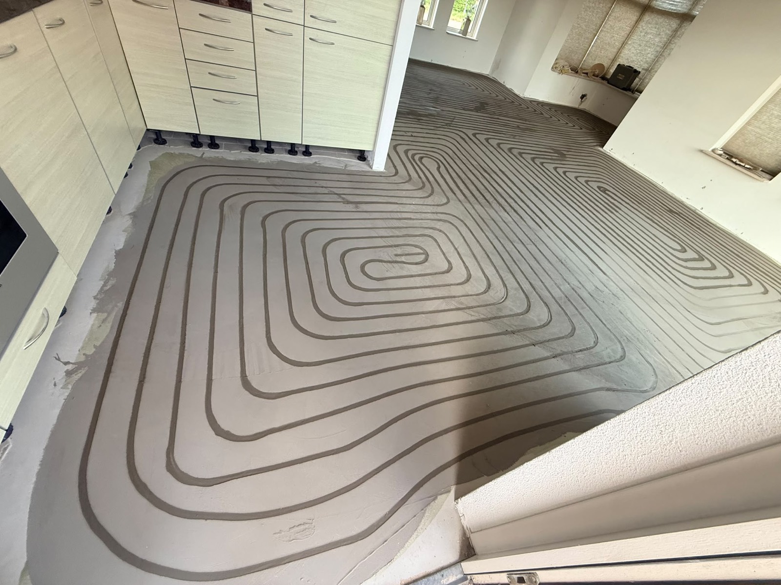 Keuken met afgewerkte dekvloer, leidingpatroon nog zichtbaar